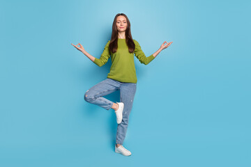 Photo of peaceful serene calm lady enjoy meditation practice wear green shirt jeans isolated blue...