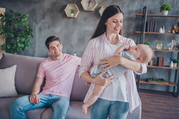 Portrait of attractive cheerful careful spouses full family rocking cute infant homey atmosphere at living room home indoors