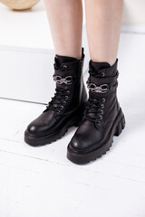 Beautiful female legs with fashionable black boots on the background in the studio. Women's stylish leather boots.