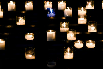 Candles lit in the church for prayers. - obrazy, fototapety, plakaty
