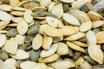 Dry Roasted Pumpkin seeds background. Tasty and healthy food. Close up photo.