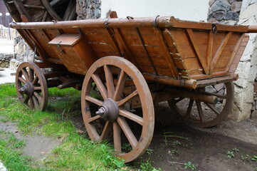 Fototapeta na wymiar An old wooden cart near the watermill. A cart with wooden wheels. An old cart for transportation. 