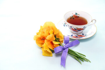 紅茶と紫のりぼんをつけたオレンジ色のパンジーの花束（白バック）