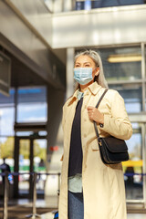 Obraz premium Woman in medical mask standing in airport terminal
