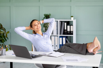 Happy female entrepreneur having time-out at workplace, dreaming while sitting on armchair and...
