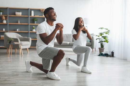Young black couple doing forward lunges exercise
