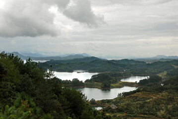 Qiandao Hu, Zhejiang Province, China: View of the lake and islands under a dramatic sky with foreground forest. Qiandao Hu translates as Thousand Island Lake and is a reservoir near Hangzhou.