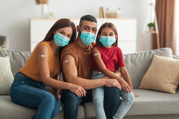 Happy Vaccinated Arab Family In Facemasks Showing Arms After Injection