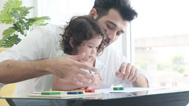 Handsome father teaching cute child daughter drawing coloring picture with pencils.