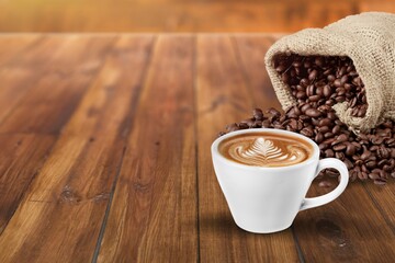 cup of coffee and coffee beans in a sack on a desk
