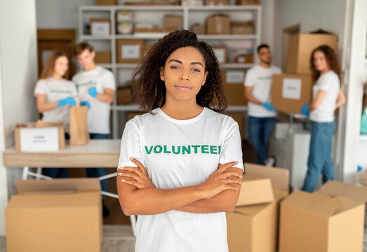 Volunteering Concept. Young African American Woman Working At Charity Center, Posing With Folded Arms To Camera