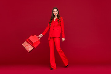 attractive woman in red with shopping bags sale on red background