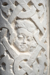 Old white stone bas-relief. Man's face in a Slavic ornament