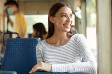 Smiling excited lady taking bus, looking at window © Prostock-studio