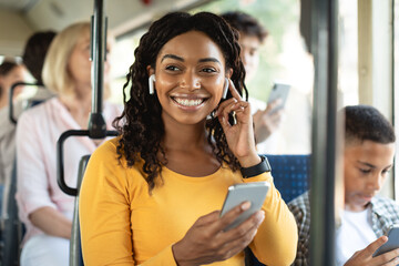 Happy black woman listening music in bus