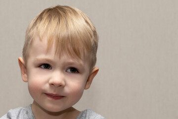 The face of a cute blond boy 3 years old close-up with facial expressions and emotions of kind and...