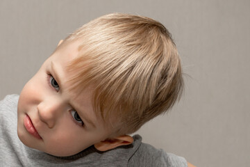 The face of a cute blond boy 3 years old close-up with facial expressions and emotions of a bully...