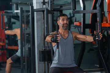 Fototapeta na wymiar Mature trainer athlete working out chest muscles doing strength training exercises on gym benchpress equipment.