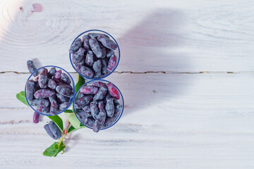 Dark blue honeysuckle berry in glass cups on a white wooden table