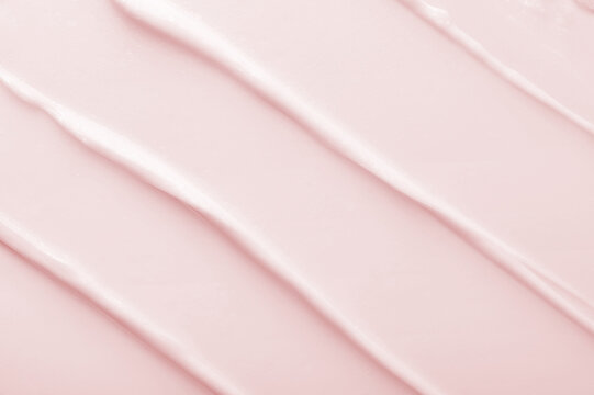 Straight strokes of light pink moisturizing cosmetic cream product pattern as color background extreme close view from above