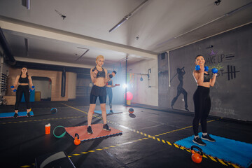 Group of good-looking sportswomen training total body fitness indoors