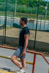 Male athlete in sportswear standing and taking a break from training in the park
