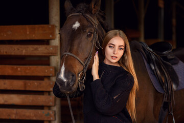 beautiful caucasian girl with a horse in the forest at sunset