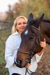 Obraz premium beautiful caucasian girl in a white shirt with a horse in the forest at sunset