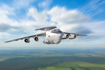 Heavy military transport aircraft with a locating and suppression device on the fuselage flies over the ground.