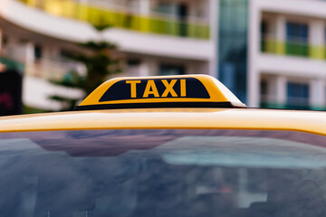 a taxi sign on the roof of a yellow car.