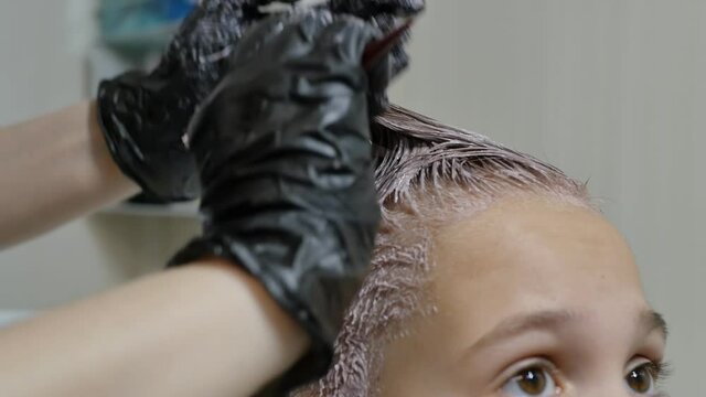 hair coloring for a teen girl. stylist hairdresser applied dye and made a hedgehog mohawk to a young client