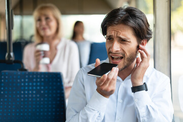 Angry man talking on phone plugging ear with finger