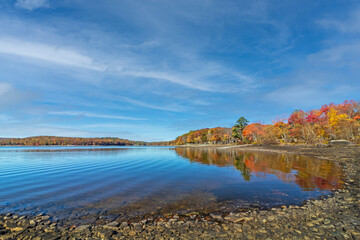 Lake Wallenpaupack in Poconos PA on a bright fall day lined with trees in vivid and beautiful foliage