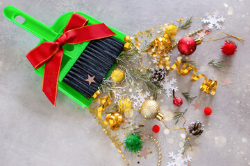 Christmas cleaning after the holiday. Broom and scoop and Christmas decorations after party on gray background. Concept of cleaning after holiday, clean up the mess.