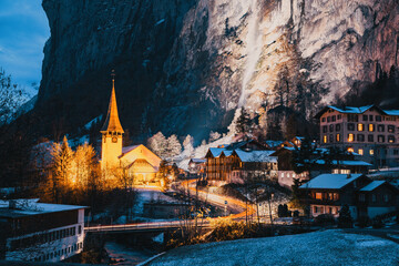 amazing touristic alpine village at night in winter with famous church and Staubbach waterfall ...