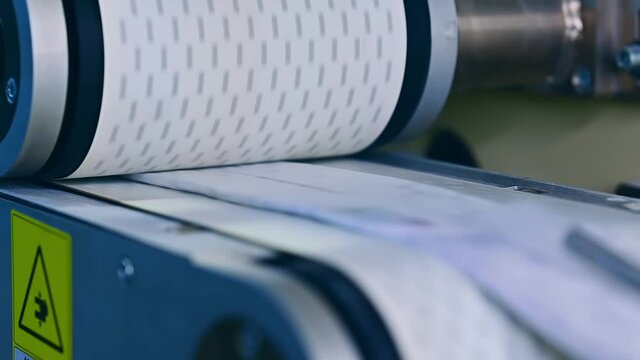 Conveyor at the factory for the production of diapers. Spinning shaft over the conveyor belt. Modern factory for producing diapers.