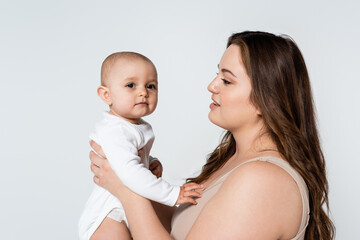 Young plus size parent looking at baby daughter isolated on grey.