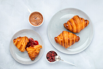 Croissants and jam. Two gray plates on a marble table. Top view, flat lay. A cup of cocoa in the morning for breakfast. Traditional French cuisine. Food background.