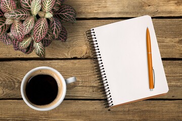 New year goals 2022 on desk. Blank notebook, coffee cup, plant on wooden table.