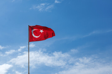 Turkish flag on flagpole waving in wind against blue sky. High quality photo
