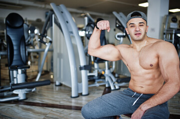 Fototapeta na wymiar Fit and muscular arabian man doing workouts in gym.
