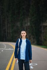 Portrait of an attractive woman in a denim shirt on a walk in the mountains, looking at the camera on a background of forest.