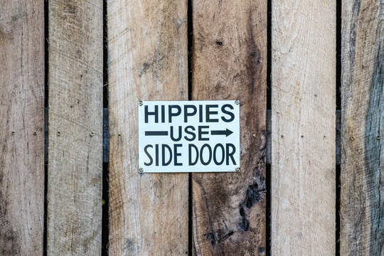 An old vintage funny humorous sign says hippies use side door showing the bias and prejudice in the culture in the 1960s and 1970s.