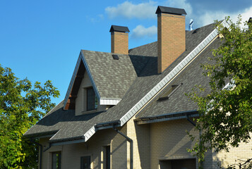A house with a pitched roofing construction with asphalt shingles installed, attic windows,...