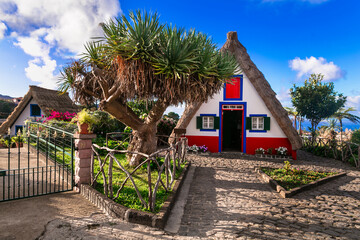 Madeira island travel and landmarks. Charming traditional colorful houses with thatched roofs in...