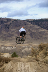 Downhill Mountain Biker at the Kamloops Bike Ranch riding a jump on Wrangler.