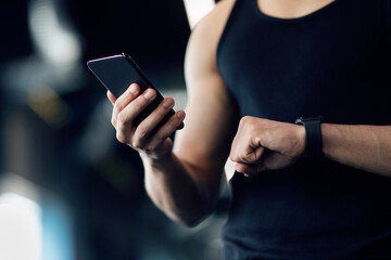 Male Athlete Using Smartwatch And Fitness App On Smartphone To Monitor Performance