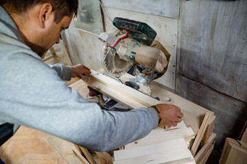 Joiner and his woodworking tools. Work in the workshop. Creation of household items from wood.