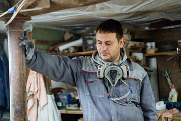 Craft. Joiner and his woodworking tools. Work in the workshop. Creation of household items from wood. Special clothes and gas mask at the carpenr