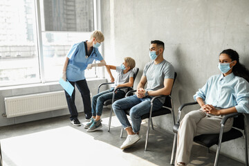 Female doctor greeting teen boy patient with elbow bump